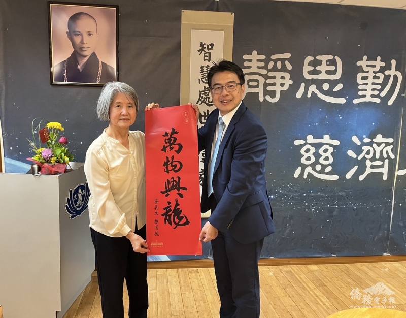 周啟宇(右)致贈蔡總統暨賴副總統春聯「萬物興龍」，由僑務委員許照惠(左)代表接受