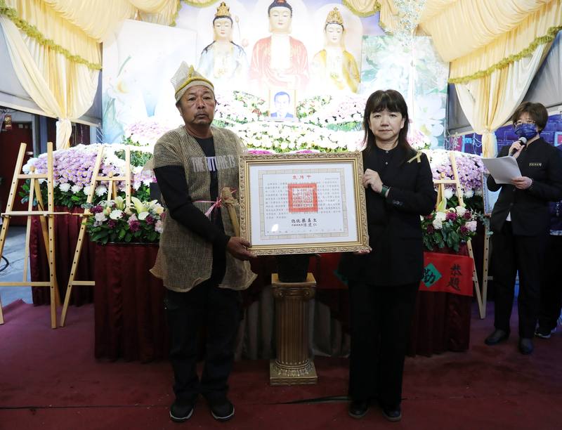 客家八音樂師鍾雲輝21日辭世，告別式30日舉行，文化部政務次長李靜慧（前右）代表頒贈總統褒揚令，由鍾雲輝家屬代表受贈