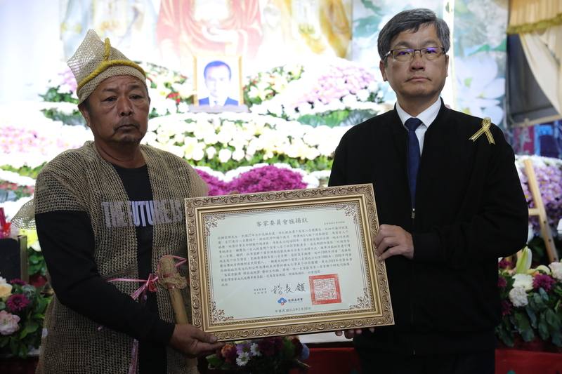 客家八音樂師鍾雲輝21日辭世，客委會主委楊長鎮（右）30日出席鍾雲輝告別式，並頒發旌揚狀，由鍾雲輝家屬代表受贈