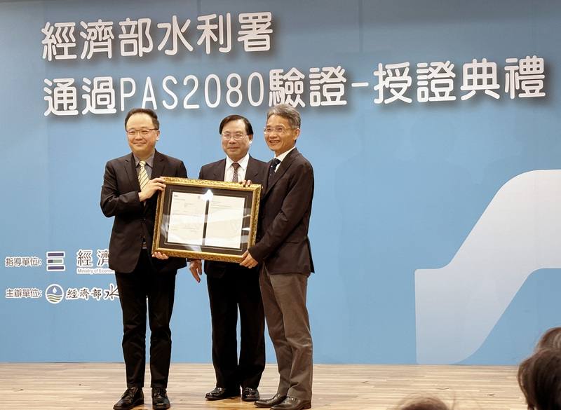水利署2日舉辦通過PAS2080驗證授證典禮，在經濟部
次長林全能（中）見證下，由BSI台灣營運長謝君豪
（左）代表頒證，水利署長賴建信（右）代表受證。