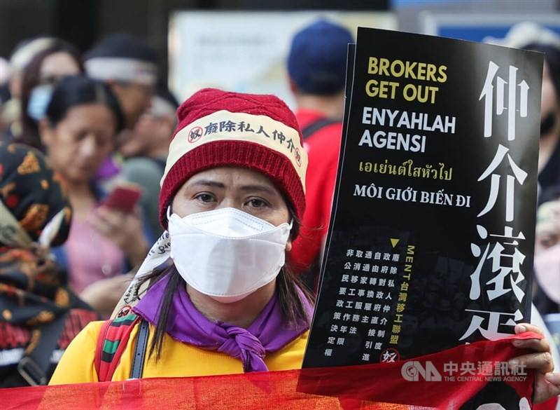 A demonstrator holds a sign calling for the elimination of the broker system during a migrant worker's march in Taipei on Dec. 12, 2023. CNA photo