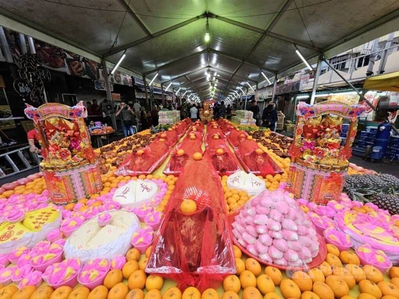 Tables of offerings including roast pork, oranges, pineapples and huat kuih (prosperity cakes). CNA photo Feb. 18, 2024