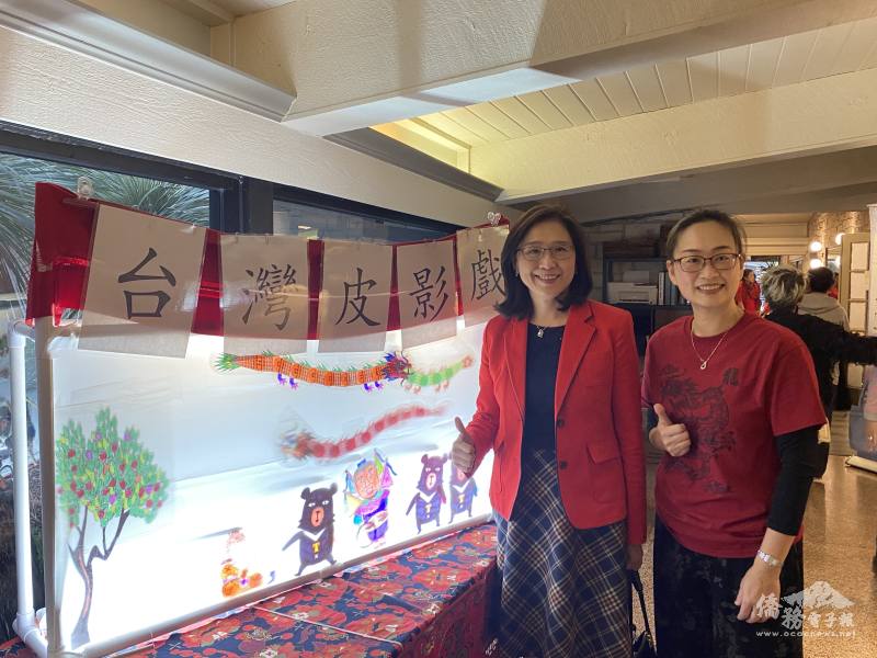 奧斯汀中文學校老師陳美杏(右)於會場入口處設置具有兒時特色的臺灣喔熊皮影戲，介紹臺灣文化