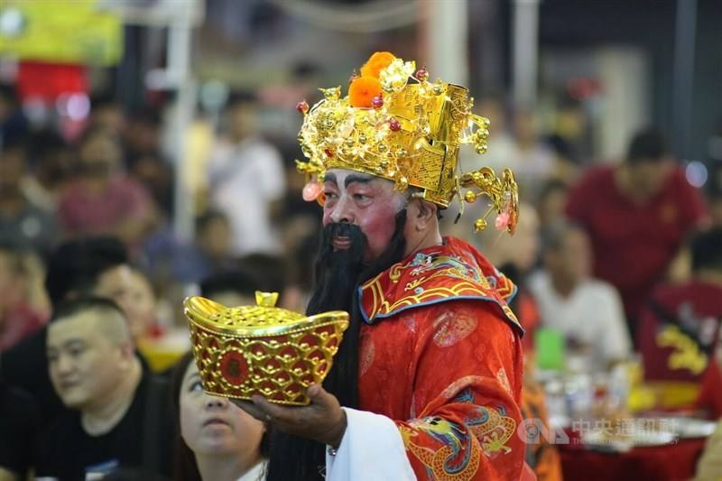 A man dressed as the God of Wealth sends blessings to worshippers. CNA photo Feb. 18, 2024