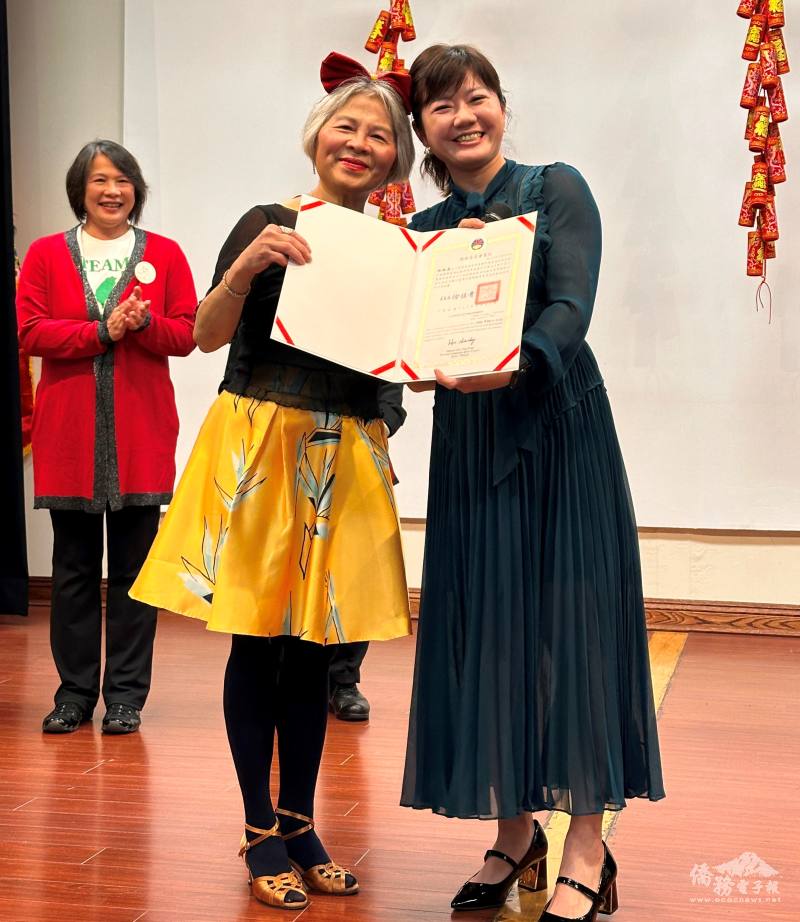 蕭蓓如(右)代表僑務委員會頒贈賀狀給新任會長林淑美(左)