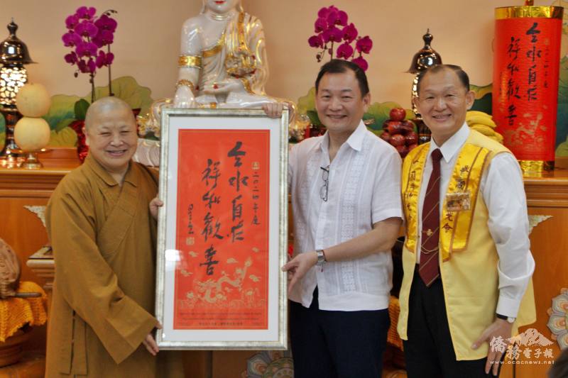 巴拉圭佛光山監寺有光法師（左一）與亞松森協會洪嘉駿會長（右一）贈送星雲大師春聯給駐巴拉圭大使館大使韓志正（中）