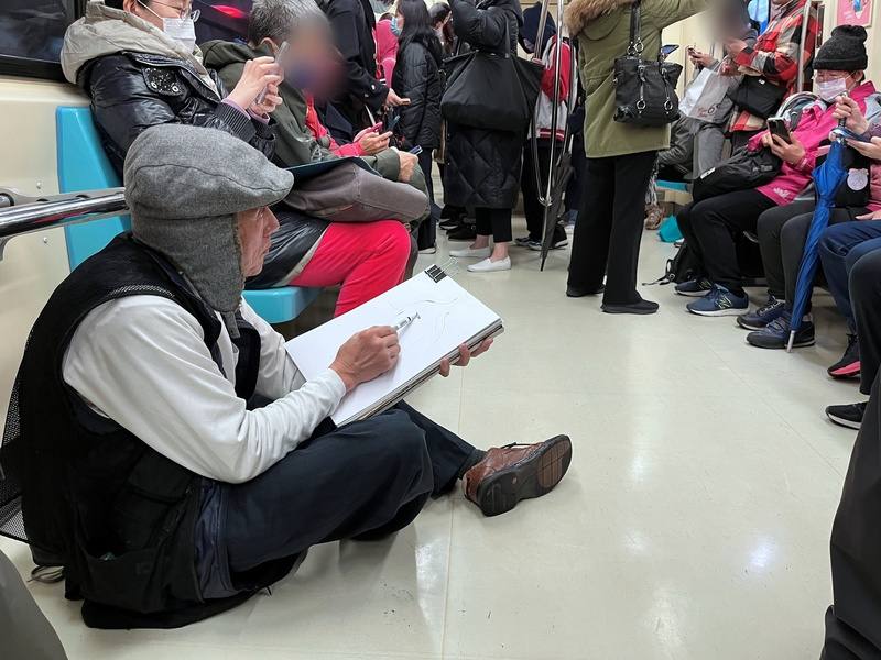 為了獲得更好的觀察角度，捷運畫家陳鈞同選擇坐在地上，仰視他的「模特兒」畫人物速寫。圖攝於113年1月25日。