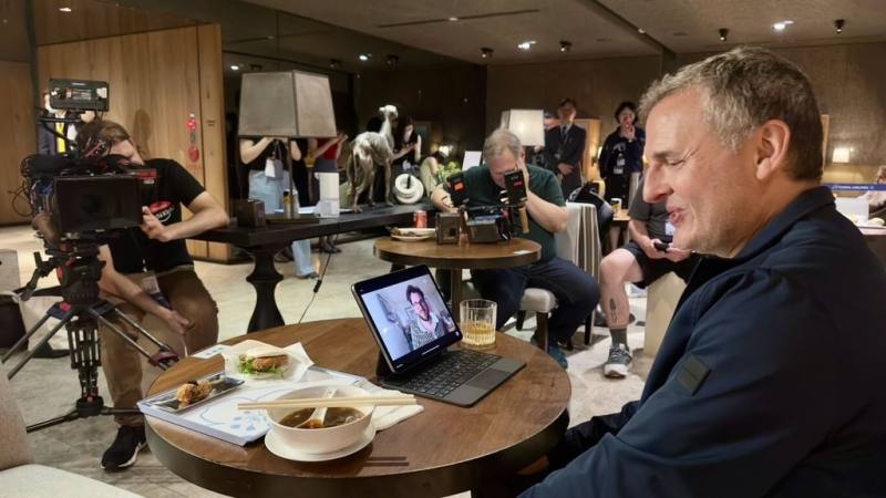 中華航空跨界合作Netflix美國節目「環球饗宴：菲爾來吃飯」，主持人菲爾（Phil Rosenthal）（右）在節目中前往華航位於桃園國際機場的貴賓室，品嚐「華航牛肉麵」的可口滋味，還透過視訊連線方式與朋友即時分享。（中華航空公司提供）