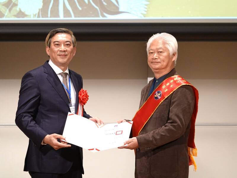 日本台灣商會聯合總會（日總）24日舉行總會長改選，第12屆總會長東鄉清龍（右）當選。駐日副代表周學佑（左）代替僑務委員會委員長徐佳青頒發賀狀