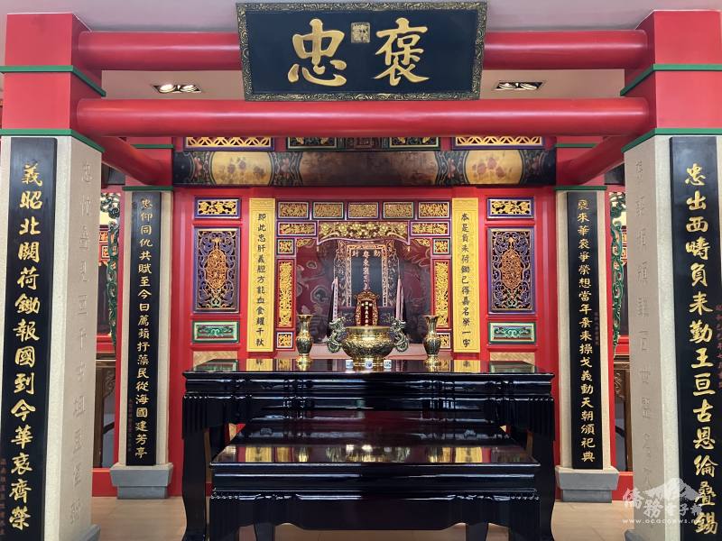 A colorful, ornate shrine housing a  black lacquered table and incense bowl.