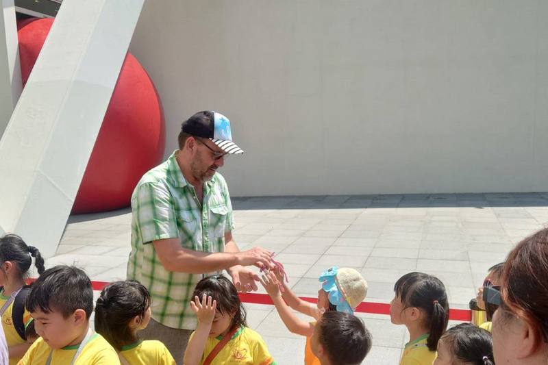 發起「紅球計畫」美國藝術家波希克（後）現身與參觀的小朋友互動。