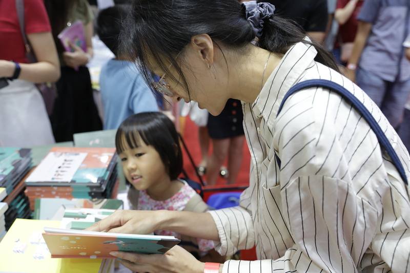 第18屆馬來西亞海外華文書市受到星馬讀者青睞，圖為母親引導女兒閱讀繪本。