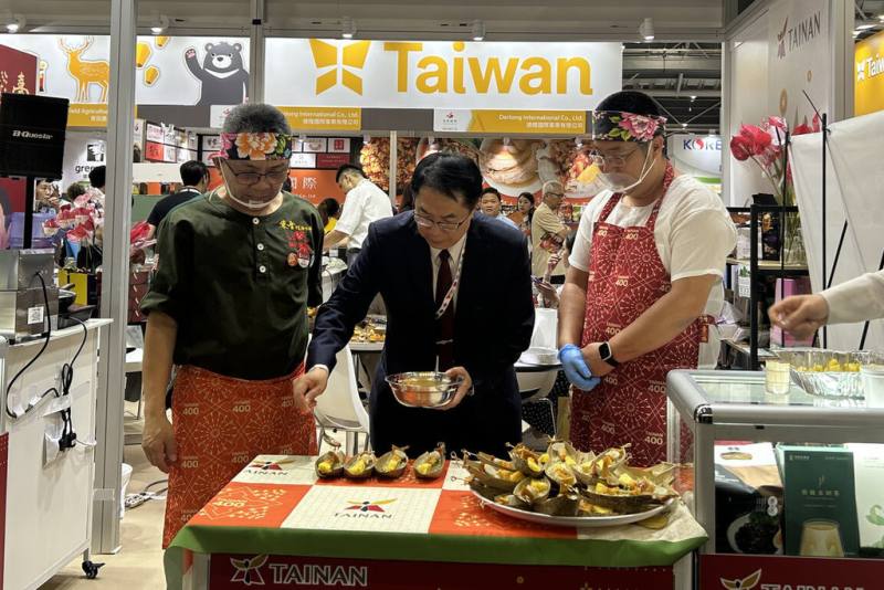 2024新加坡國際食品展23日開幕，台南市長黃偉哲（前中）帶隊行銷農特產，並於現場協助主廚製作試吃料理。（台南市政府提供）
