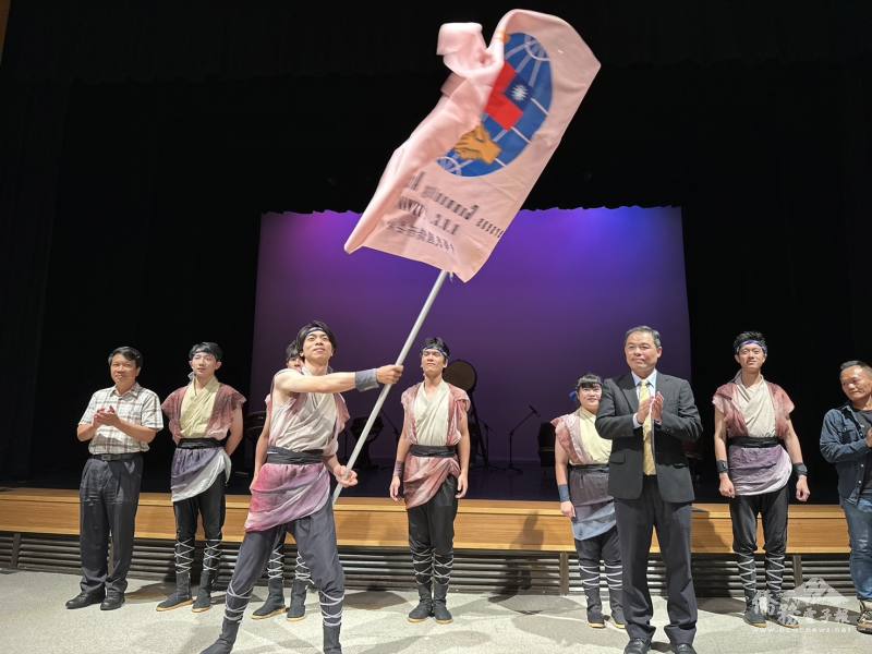 僑委會僑教處處長黃正杰（前排右）授旗予十鼓擊樂團謝懷玨藝術總監（前排左）