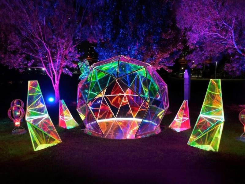 與草地上樹影相互映襯的「幻彩之花」創作地景10日起在新北大都會公園展出，如鑽石般耀眼視覺效果，忽明忽滅，營造出如夢似幻春夜魔幻島嶼景象。（新北市高灘處提供）