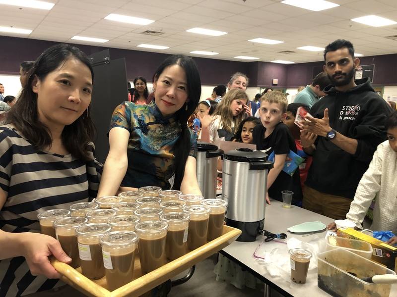 台灣媽媽柳超端（前右）、吳美萱（前左）在美國維吉尼亞州獵人伍茲小學校園擺設台灣攤位，自製珍奶吸引大排長龍