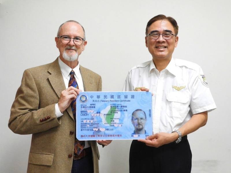 來自美國的李參（Geoffrey Lasley）（左）來台生活逾37年，從事英文教學工作，近日獲頒馬偕計畫永久居留證，感謝他對台灣教育的付出。（移民署中區事務大隊台中市第一服務站提供）