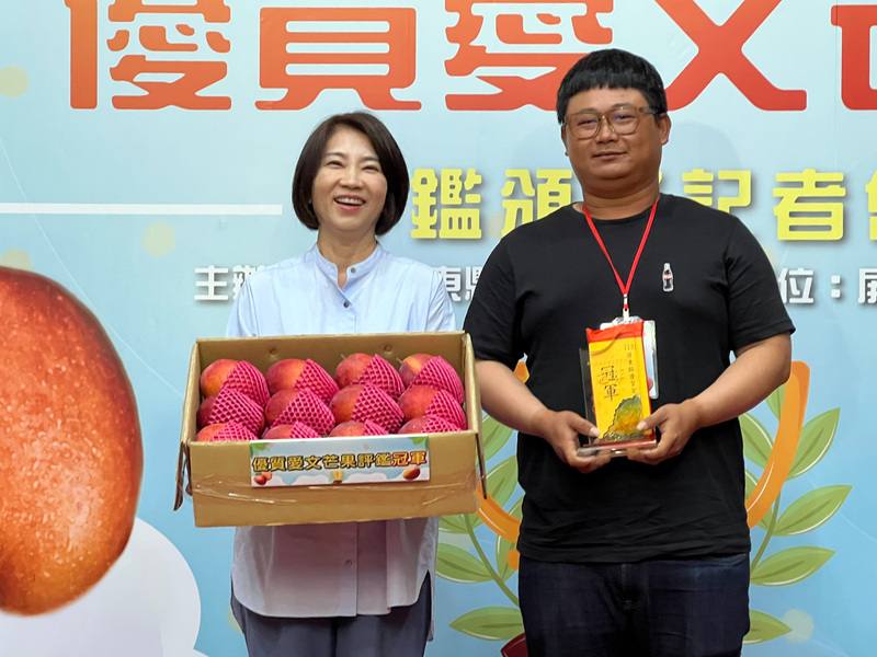 屏東愛文芒果進入產季，縣府鼓勵農民更具市場競爭力，舉辦評鑑會，28日下午由縣長周春米（左）揭曉結果並頒獎表揚，冠軍由枋寮地區農會輔導的果農林仕維（右）奪下。