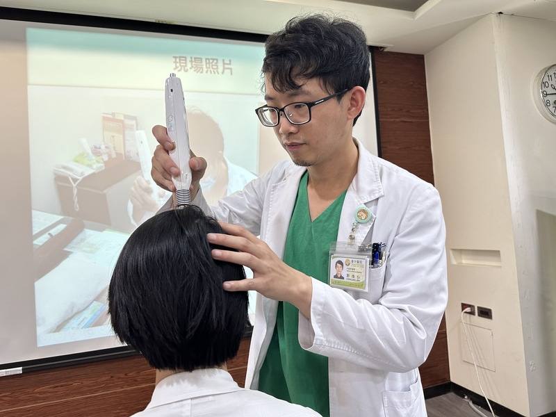 衛福部台中醫院中醫師鄭惟仁（右）31日指出，雷射針灸治療不只可用於自閉兒治療，包括1歲以上害怕疼痛與針灸族群、促進慢性傷口癒合、治療運動員肌肉痠痛或扭傷等，都是雷射針灸治療的主要族群。圖為鄭惟仁在記者會現場示範以雷射針灸位於頭頂的百會穴