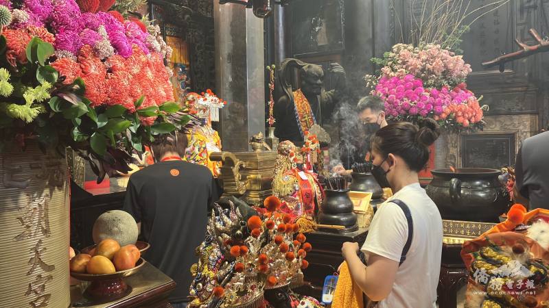 Worshippers offering gifts, surrounded by the smoky, incense-filled interior of Chaotian Temple