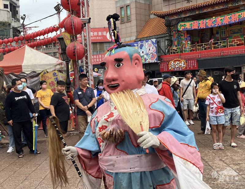 Portraying a smiling, dimpled god, a performer runs and jumps through the crowd, waving his fan and wand.