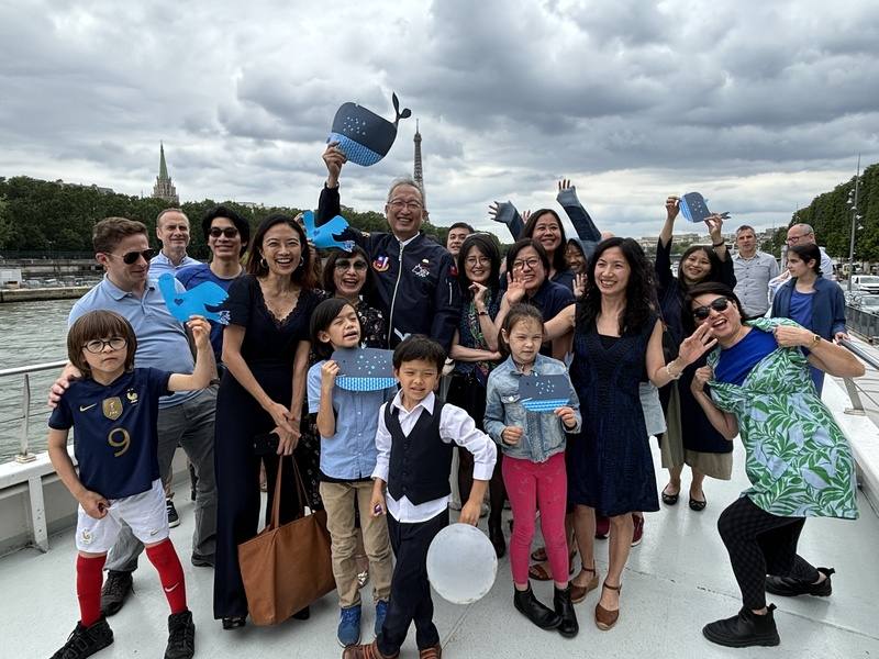 6月30日歡送會上僑胞邀請駐法代表吳志中（中，高舉右手者）在巴黎鐵塔前共同拍攝變裝皇后妮妃雅募集前進巴黎奧運的創意影片，結合藍、綠兩個小隊，象徵台灣團結。