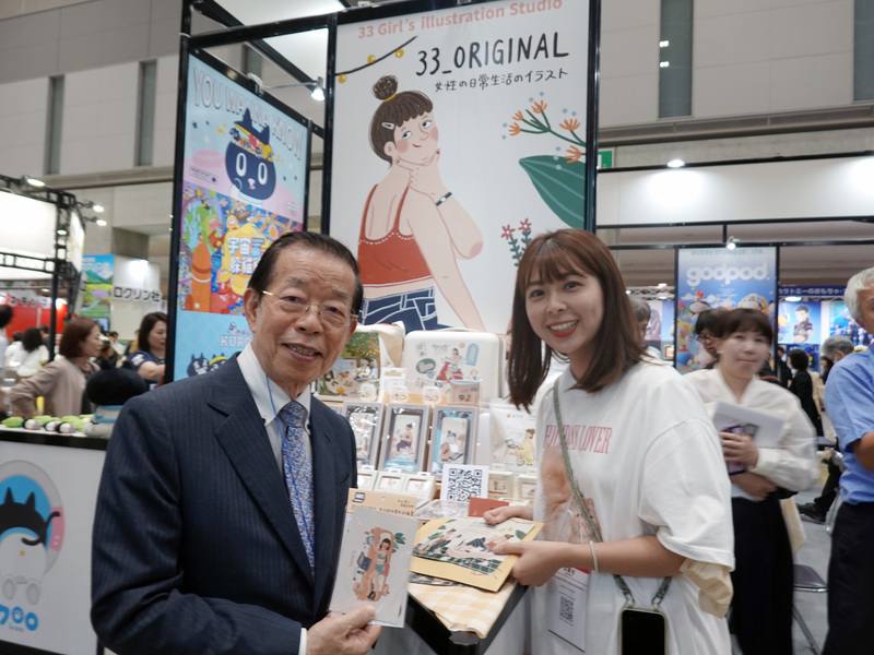 駐日代表謝長廷（前左）3日出席日本授權展台灣館開幕式，並走訪台灣館攤位，與描繪真實女性生活的「33_ original女子的日常生活插畫」創作者（前右）合影。