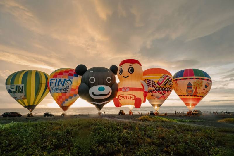 台東太麻里曙光園區15日舉行熱氣球嘉年華光雕音樂會，天未亮湧入不少遊客，看著6顆繽紛熱氣球豎起，在沙灘上迎接曙光。（台東縣政府提供）