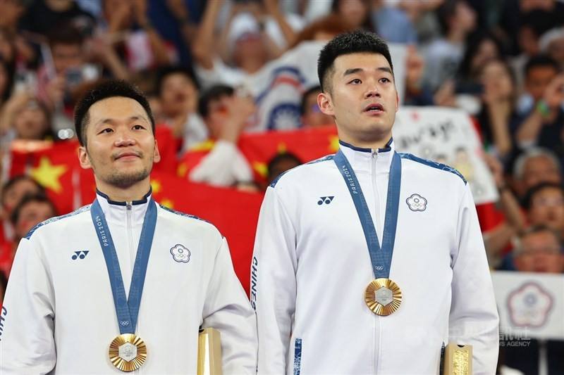 Taiwanese badminton duo Lee Yang (left) and Wang Chi-lin stand on the award podium with their gold medal at the Olympics on Sunday. CNA photo Aug. 4, 2024