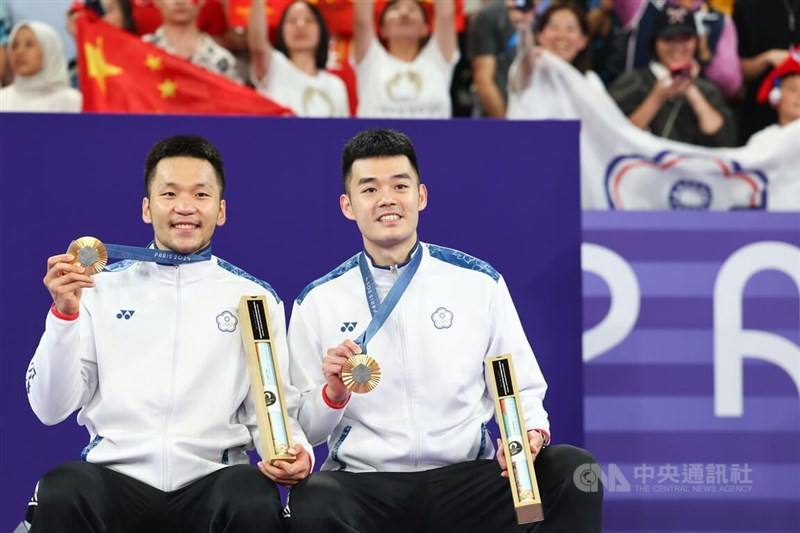 Taiwanese badminton duo Lee Yang (left) and Wang Chi-lin hold their gold medals at the awards ceremony at the Paris Olympics on Sunday. CNA photo