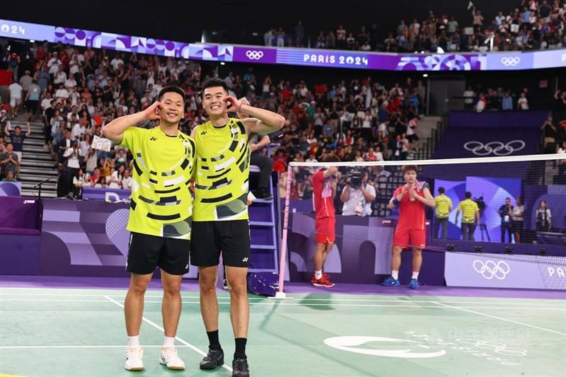 Taiwanese badminton duo Lee Yang (left) and Wang Chi-lin make a heart sign after winning the gold medal match. CNA photo