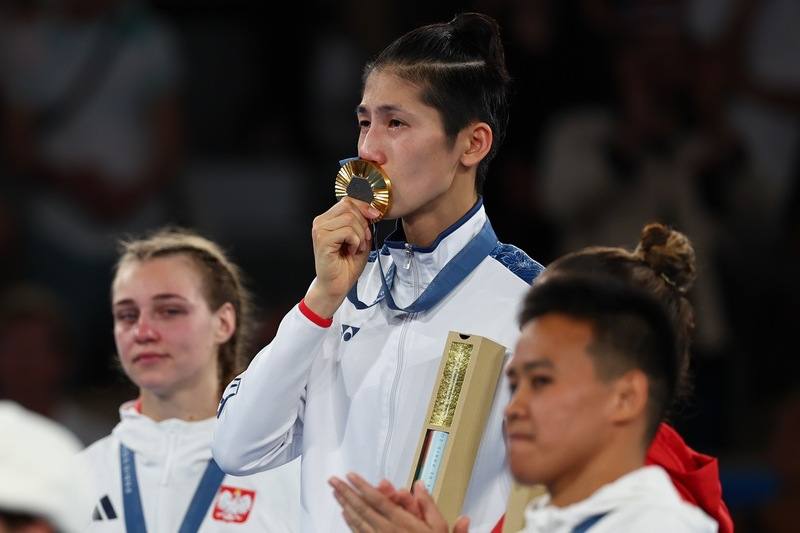 台灣拳擊女將林郁婷（中）征戰2024巴黎奧運一路艱辛，法國時間10日晚間成功用實力證明自己、拿下57公斤級賽事金牌，頒獎後她在台上拿起獎牌輕吻。