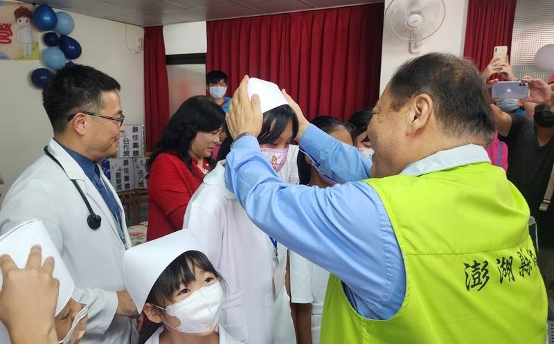 澎湖30名小朋友13日化身「小小南丁格爾」，實地體驗護理師工作，縣長陳光復（前右）逐一為他們加冠