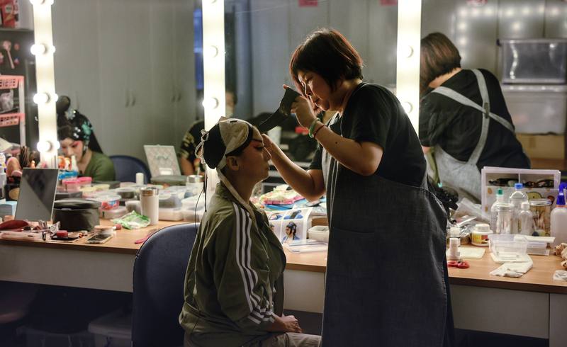 國光劇團箱管組組長、負責包頭容妝的張美芳（右）是大鵬劇校出身，明白每名演員要站到台前，必須經過無數次練習、下許多苦功，因此每一場演出無論大小，她都盡力為演員包頭變髮、妝扮頭飾