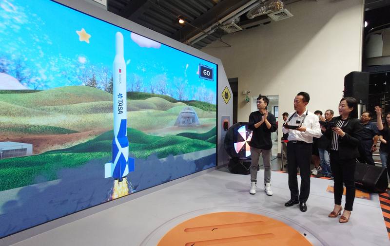 「5G無限宇宙」主題展28日起在嘉義縣北回二館太空教育館正式啟動，嘉義縣長翁章梁（前右2）、數發部數位產業署主秘黃雅萍（前右）現場以平板體驗5G太空數位遊戲