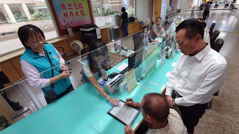 嘉義縣財政稅務局使用「臨櫃申辦無紙化運用電子紙系統」，縣長翁章梁（右）29日現場觀看民眾申請過程指出，運用此技術每年可節省數萬張紙張