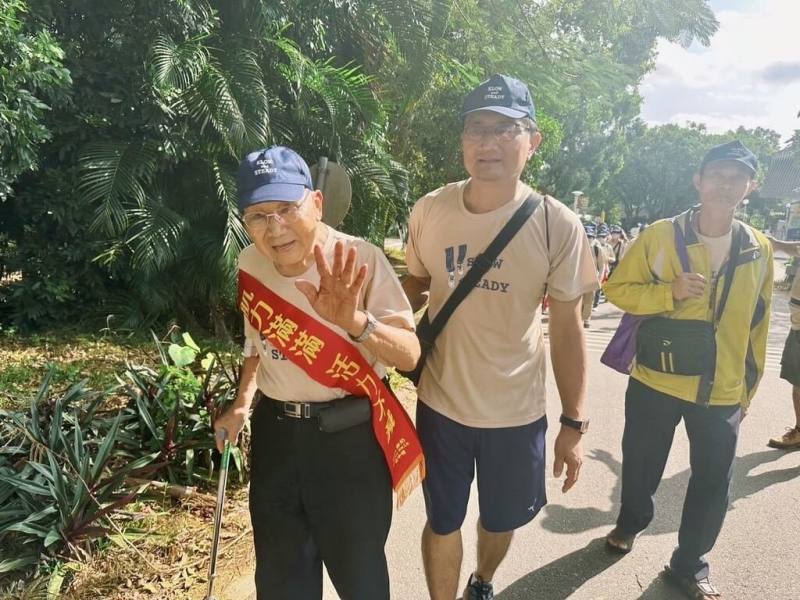 弘道老人福利基金會舉辦「爺奶Color Walk」健走活動，10日在東海大學登場。99歲戴紀彬（左）是最高齡參賽者，再過1個月將邁入100歲的他，在兒子（前右）陪伴下挑戰健走3公里。（弘道老人福利基金會提供）