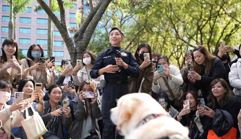 退休警犬「福星」30日現身新北市參與「2024毛寶貝魔幻幸福耶誕趴」，與領犬員林志倫（中）互動，也受到大批民眾熱烈歡迎。（新北市警察局提供）
