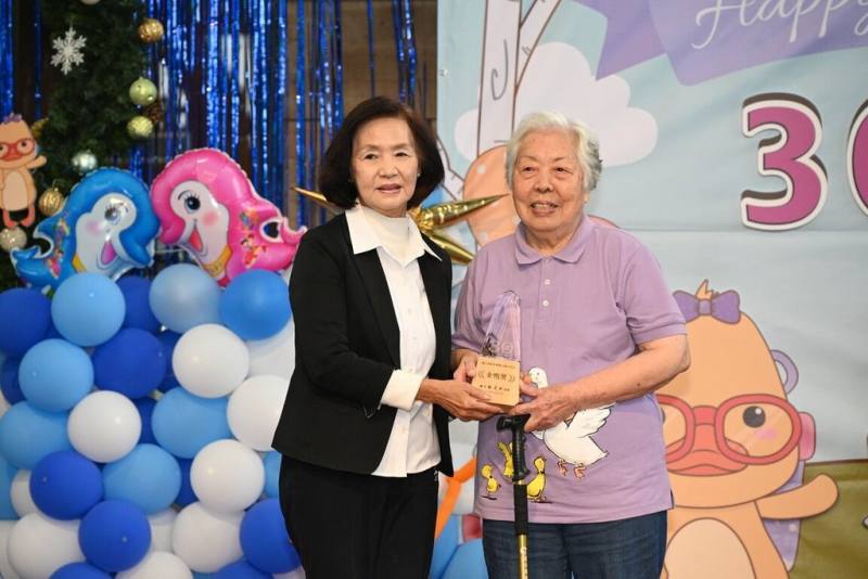 宜蘭縣「醜小鴨故事劇團」成立滿30年，縣府7日頒發獎座給資深志工，服務滿30年、高齡95歲的阿嬤孫儒先（右）開心從縣長林姿妙（左）手中接下獎座，也說「我還要一直講故事到100歲」。（宜蘭縣政府提供）