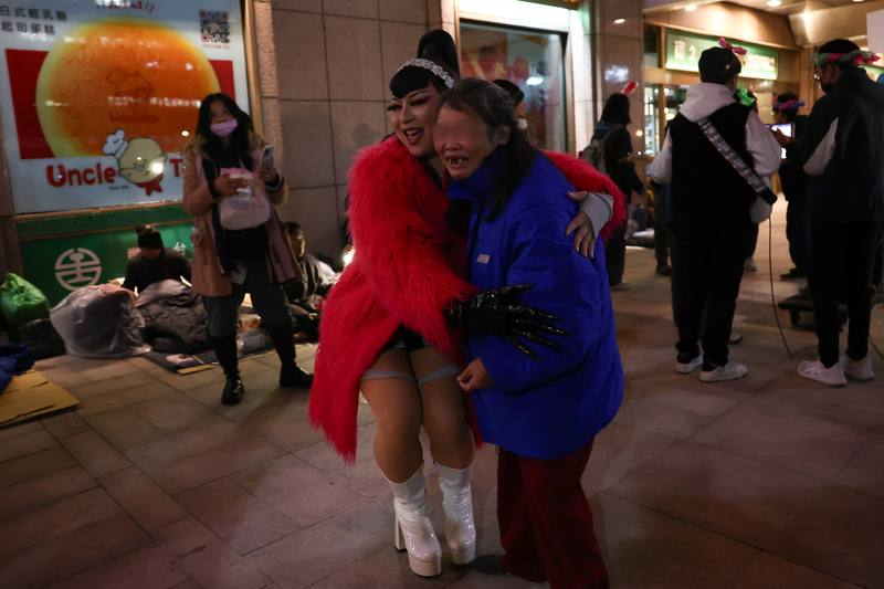 Drag queen Hana Boo Boo (left) hugs a homeless individual during a performance at a year-end banquet outside Taipei Main Station on Friday. CNA photo Jan. 18, 2025