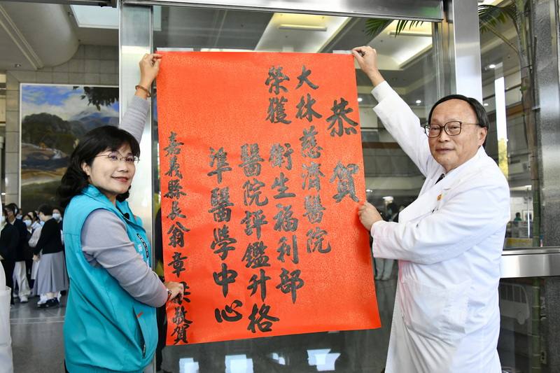 大林慈濟醫院升格準醫學中心，24日下午舉辦感恩儀式，嘉義縣衛生局長趙紋華（左）也代表縣長翁章梁前來貼紅榜祝賀。右為大林慈濟醫院院長賴寧生