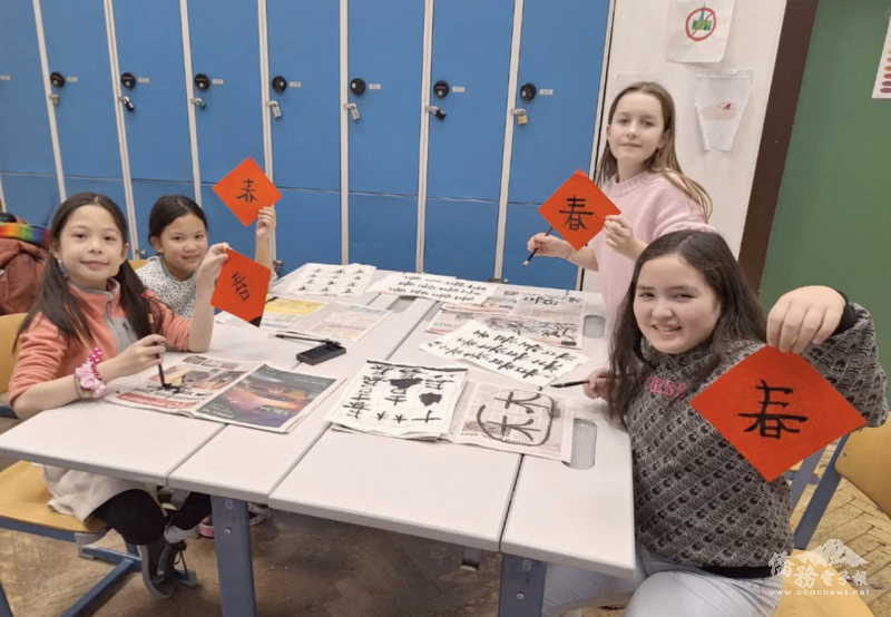 孩子們開心地展示自己親手書寫的作品，紅紙上的「春」字象徵新年的來臨。新春書法體驗活動不僅讓他們學習了毛筆書寫的技巧，也感受到臺灣春節的文化魅力