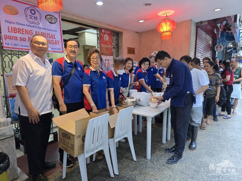 菲華文經總會幹部們分送水煮蛋、麵包及餅乾給排隊民眾