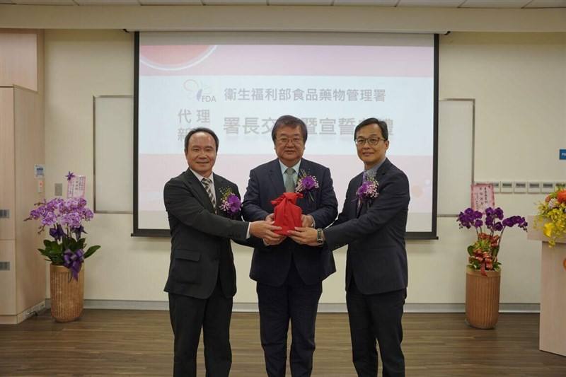 The new Taiwan Food and Drug Administration Director-General Chiang Chih-kang (right) receives the baton from acting director Lin Chin-fu (left) at his appointment ceremony Thursday, as Health Minister Chiu Tai-yuan (center) looks on. Photo courtesy of Mi