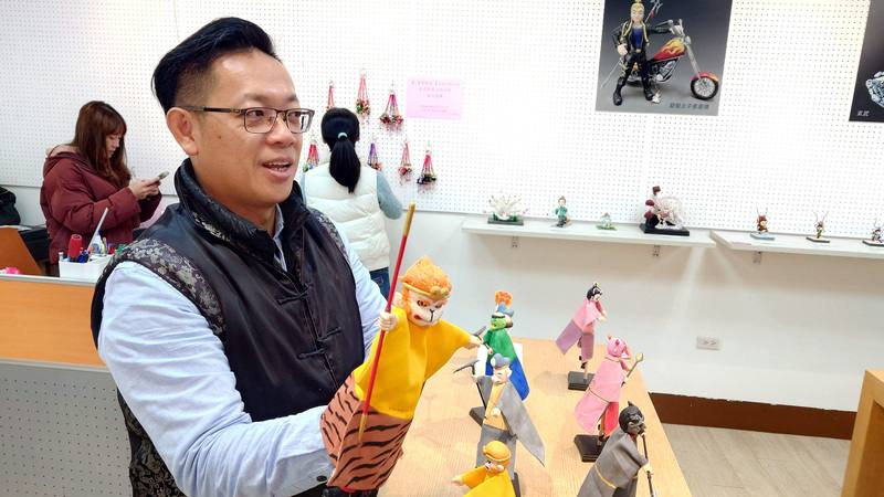 捏麵人藝師黃昭智（前）將布袋戲偶木雕的戲偶頭，改用捏麵人方式製作，讓布袋戲與捏麵人兩項傳統藝術相融合，正在嘉義縣竹崎文化藝術基金會舉辦個展