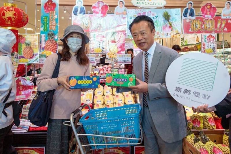 嘉義縣「嘉義優鮮－鳳梨嘉年華」販售活動23日在日本山口縣丸久超市防府店登場，縣長翁章梁（右）特別向民眾推銷首次上架的鳳梨酥。（嘉義縣政府提供）