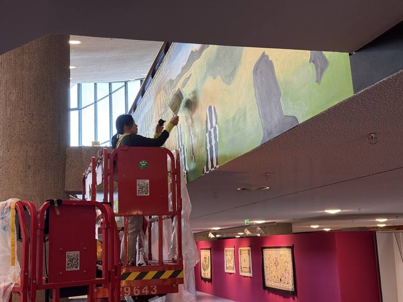 宜德思．盧信於柏林世界文化之家搭乘升降梯繪製壁畫，她於布展期間接受中央社採訪表示，比起印刷輸出，她更喜歡現場直接作畫。不過繪製壁畫時因載體與當地氣候差異，也會迎來不同挑戰