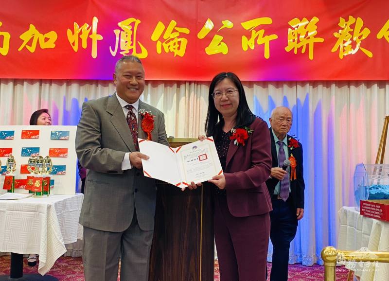 洛杉磯文教中心主任鍾佩珍(右)代表僑務委員會委員長徐佳青致頒賀狀予連任主席司徒偉根(左)