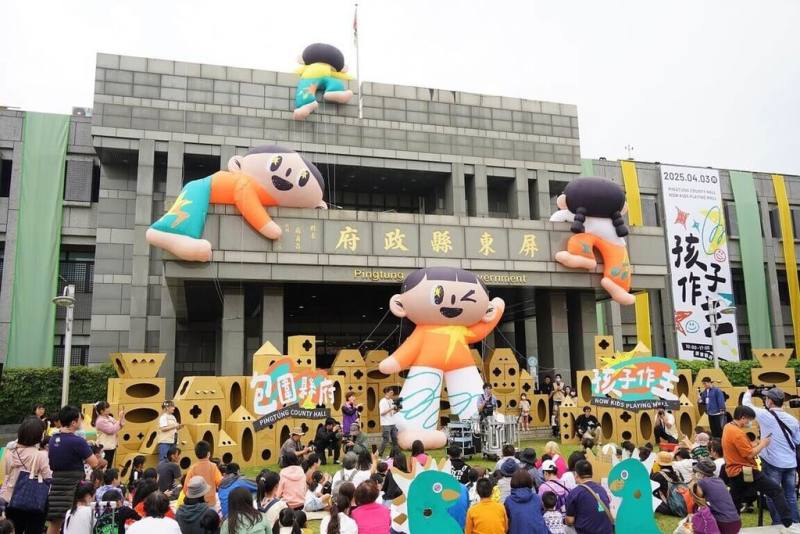 屏東縣政府3日舉辦「包圍縣府 孩子作主」兒童節活動，縣府大樓外牆有4個巨型人偶，有緊抓著窗框人偶，也有俏皮探頭張望的人偶，就像是在進行一場「孩子當家」冒險行動。（屏東縣政府提供）