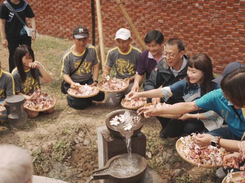 高雄市「美濃文化生態散步策」以地方特色之一「湧泉」為主題，打造一條南北向散步路徑，9日舉辦啟用典禮，與會者們在博士泉旁灑下花瓣，象徵對湧泉的尊重與祝福。（高雄市政府客家事務委員會提供）